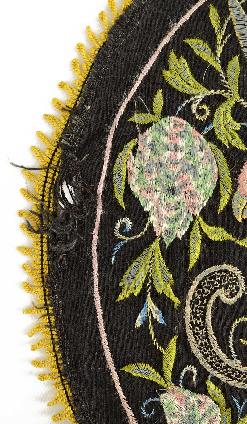 Antique embroidered parrot on perch.