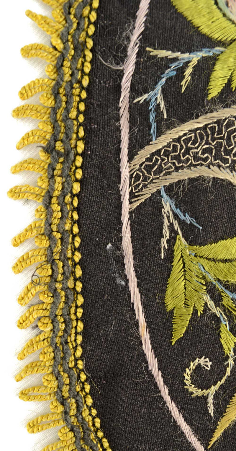 Antique embroidered parrot on perch.